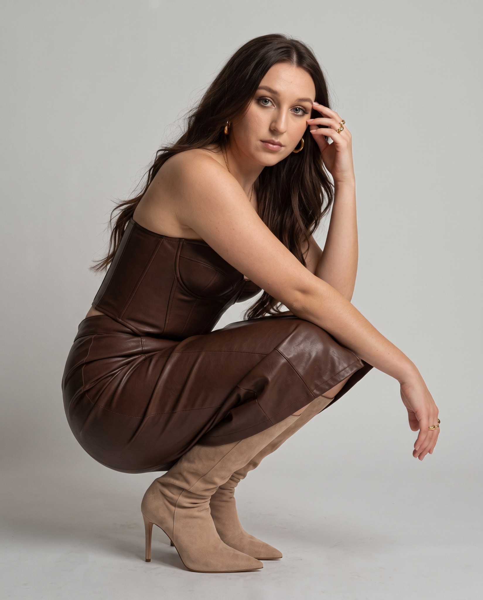 Eva in a chocolate brown outfit, crouching in a studio